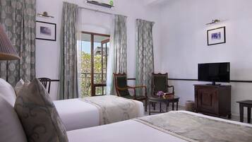 A hotel room with two beds, a television, a chair, and a small table.