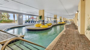 Zona de piscina con suelo de baldosas, aros flotantes amarillos y un camino de ladrillo.