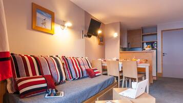 A compact living space with a sofa, a dining table, and a kitchenette.