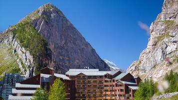 A mountain lodge with multiple floors, balconies, and a view of a steep mountain.