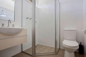 Casa de banho moderna com cabine de duche em vidro, lavatório branco e sanita.