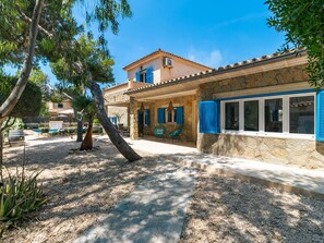 A stone building with a tiled roof, a stone wall, and a window with blue shutters. - Villa Azul by Interhome (Santanyí)
