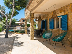 Ein Steinhaus mit überdachter Terrasse, Gartenmöbeln und einem Pool.