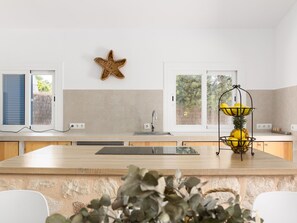 A modern kitchen with a central island, a star decoration on the wall, and a fruit basket on the counter. - Villa Azul by Interhome (Santanyí)