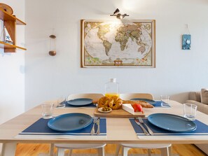 A dining area with a world map on the wall, a wooden table set for breakfast, and a bookshelf with nautical-themed decor. - Apartment  by Interhome (Portocolom)