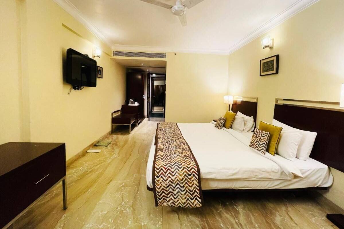 A hotel room with a bed, bedside table, TV, and a ceiling fan.