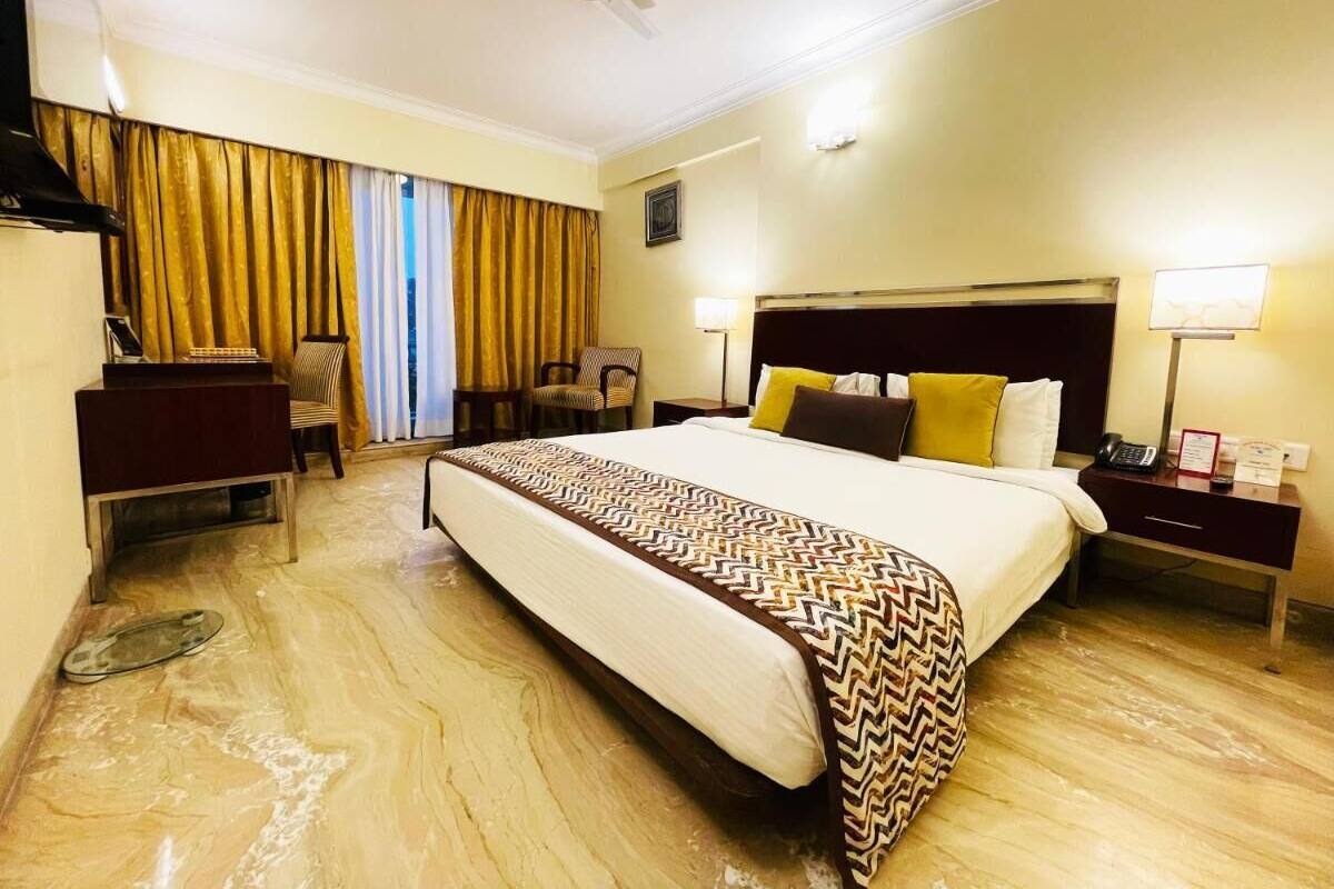 A hotel room with a bed, a desk, a chair, a telephone, and a ceiling fan.