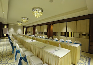 A conference room with a long table, chairs with blue sashes, and chandeliers. - The Wall Street (Jalsu)