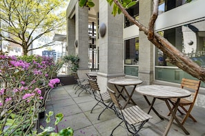 An outdoor seating area with tables and chairs, a stone wall, and a tree with pink flowers. - Best capital hill  location studio close to fun w/
free parking / fitness center (Seattle)