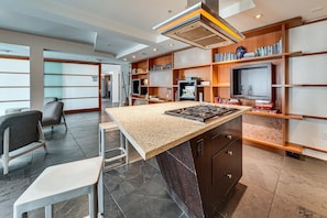A modern kitchen with a central island, built-in bookshelves, and a large window. - Best capital hill  location studio close to fun w/
free parking / fitness center (Seattle)