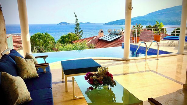 A covered outdoor area with a pool, a sofa, and a table with flowers. - Amazing 4-bedroom seafront villa with infinity pool in Kalkan (Kaş)