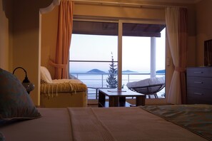 A hotel room with a bed, a small table, a chair, and a view of the sea. - Amazing 4-bedroom seafront villa with infinity pool in Kalkan (Kaş)
