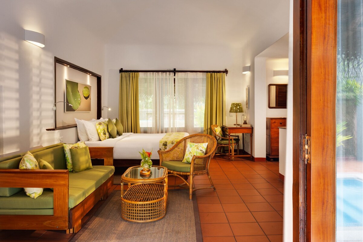 A hotel room with a bed, a sofa, a chair, a small table, and a desk.