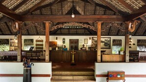 A reception area with a wooden ceiling, a reception desk, a lamp, and a small table with a box. - Marari Beach Resort - A CGH Earth Experience (Cherthala)