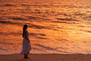 A beach scene with waves and a person in a white dress. - Marari Beach Resort - A CGH Earth Experience (Cherthala)