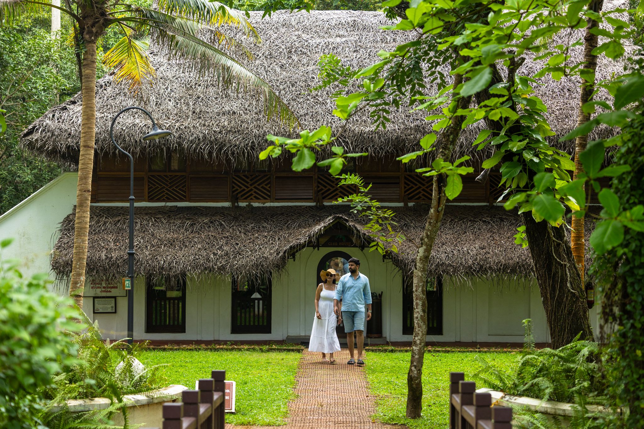 A thatched-roof building with a paved walkway leading to an entrance.