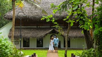 A thatched-roof building with a paved walkway leading to an entrance.