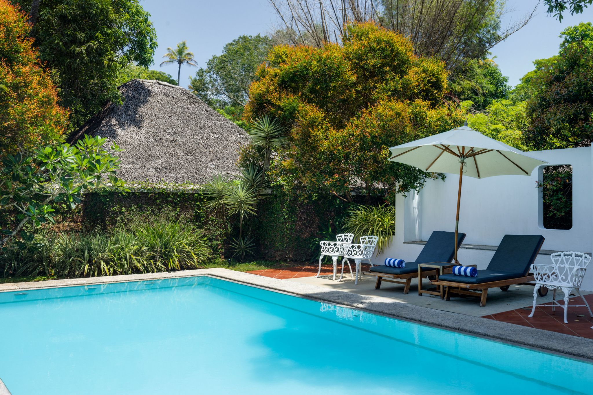 A swimming pool with lounge chairs and a thatched-roof structure.