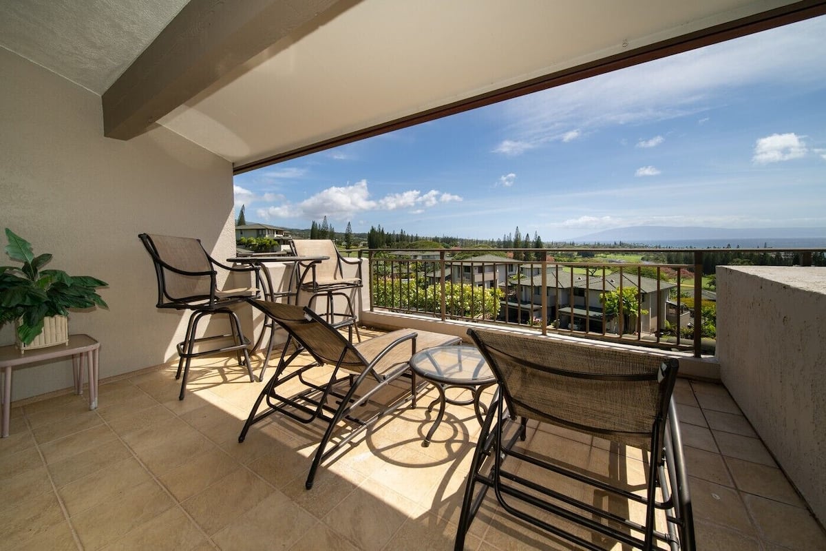 Ein Balkon mit Stühlen und Tisch, mit Blick auf eine Wohngegend mit Häusern und Grünflächen.