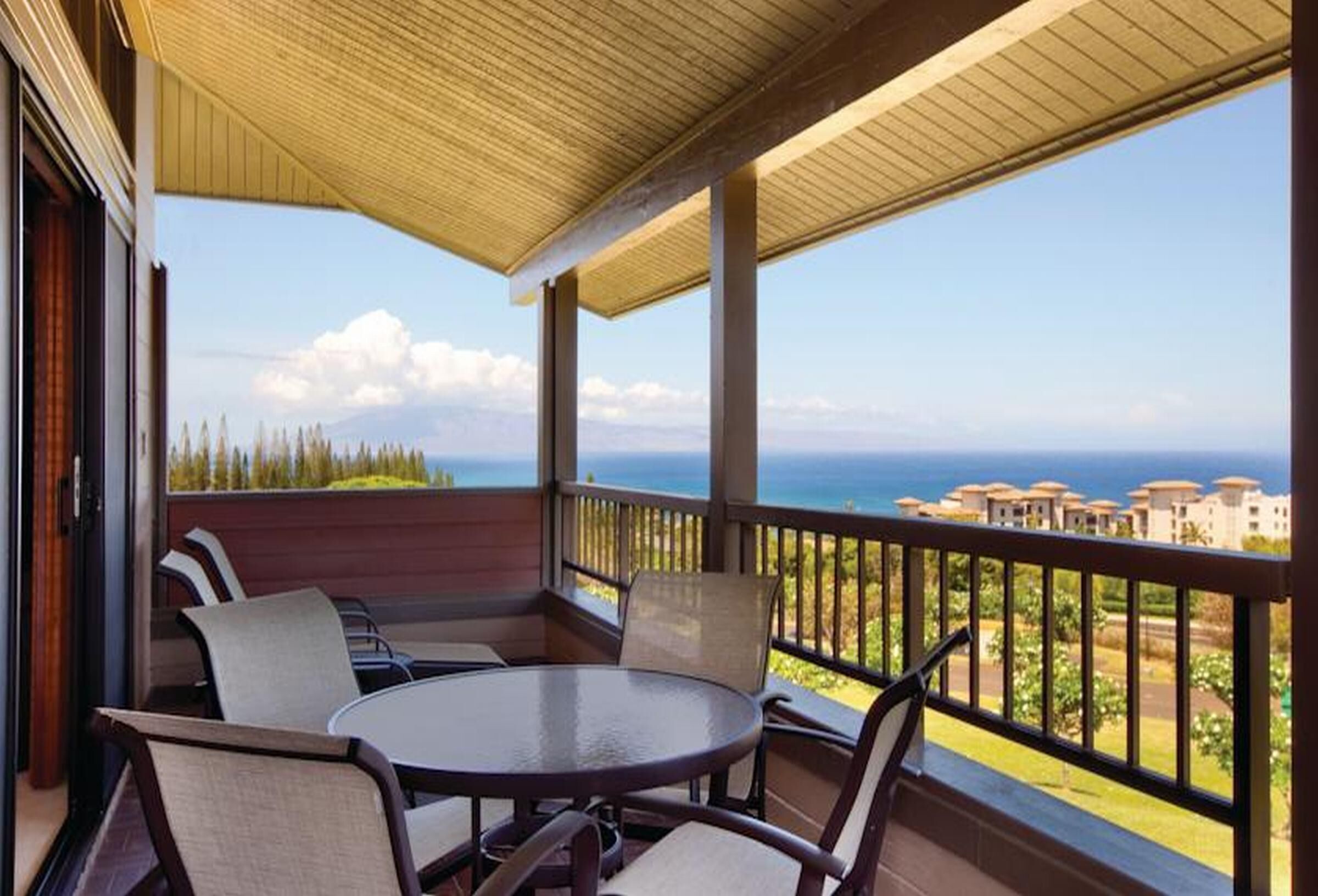 A covered outdoor seating area with a view of the ocean and buildings in the distance.