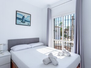 Ein Hotelzimmer mit einem Bett, einem Nachttisch, einem Gemälde und einem Fenster mit Vorhängen.