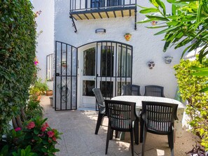 Eine Terrasse mit Tisch und Stühlen, eine weiße Wand mit Dekoration und ein Tor.