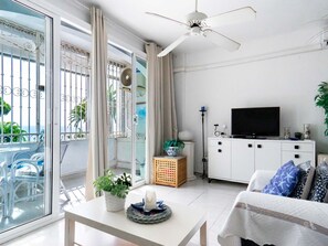 Ein modernes Wohnzimmer mit einem Flachbildfernseher, einem Deckenventilator und einem Balkon mit Blick.