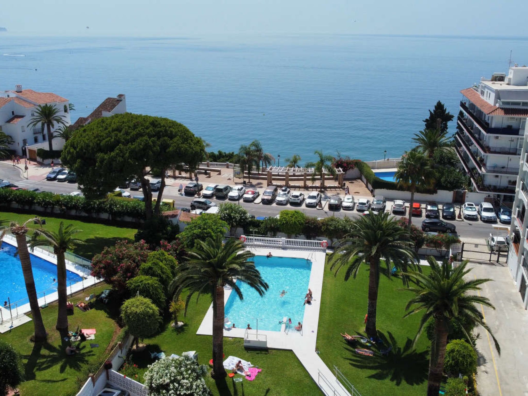 A resort with a swimming pool, parking area, and ocean view.