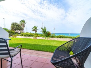 Eine Terrasse mit Meerblick, ein Stuhl, ein Tisch und ein gepflegter Rasen.