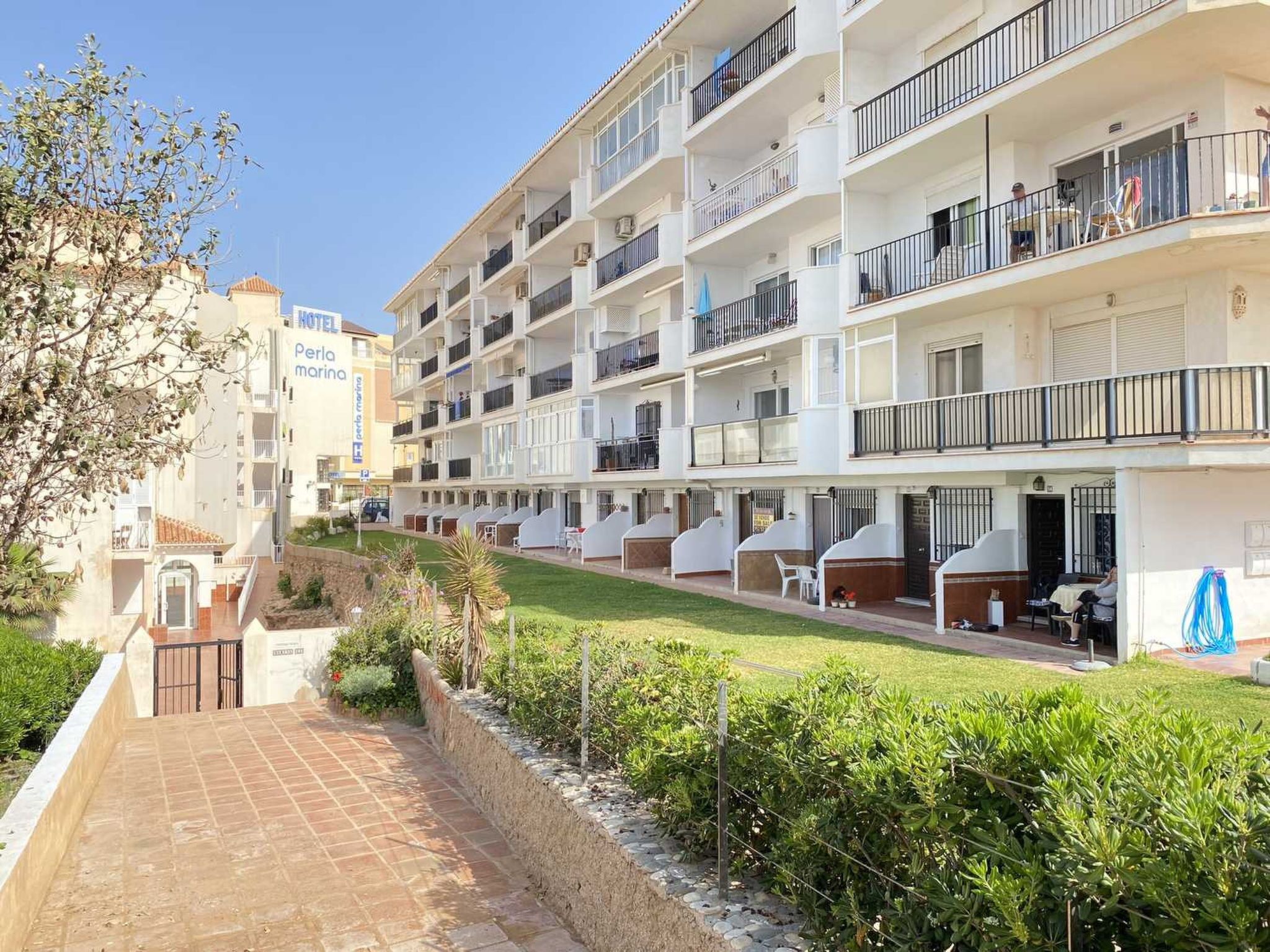 Ein mehrstöckiges Hotel mit Balkonen, einem Schwimmbad und einem Garten.