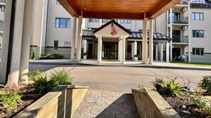 A hotel entrance with a covered walkway, American flag, and a sign indicating a danger warning.