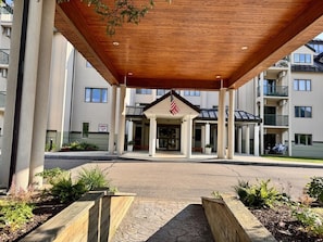 A hotel entrance with a covered walkway, American flag, and a sign indicating a danger warning.