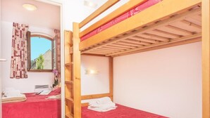 A room with a bunk bed, a window with curtains, a small shelf, and a wall-mounted light. - Residence Village Vignec (Vignec)