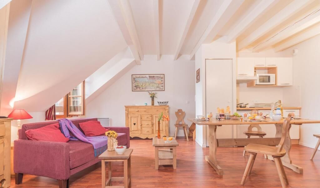 A cozy loft-style living space with a dining area, wooden furniture, and a kitchen with modern appliances.