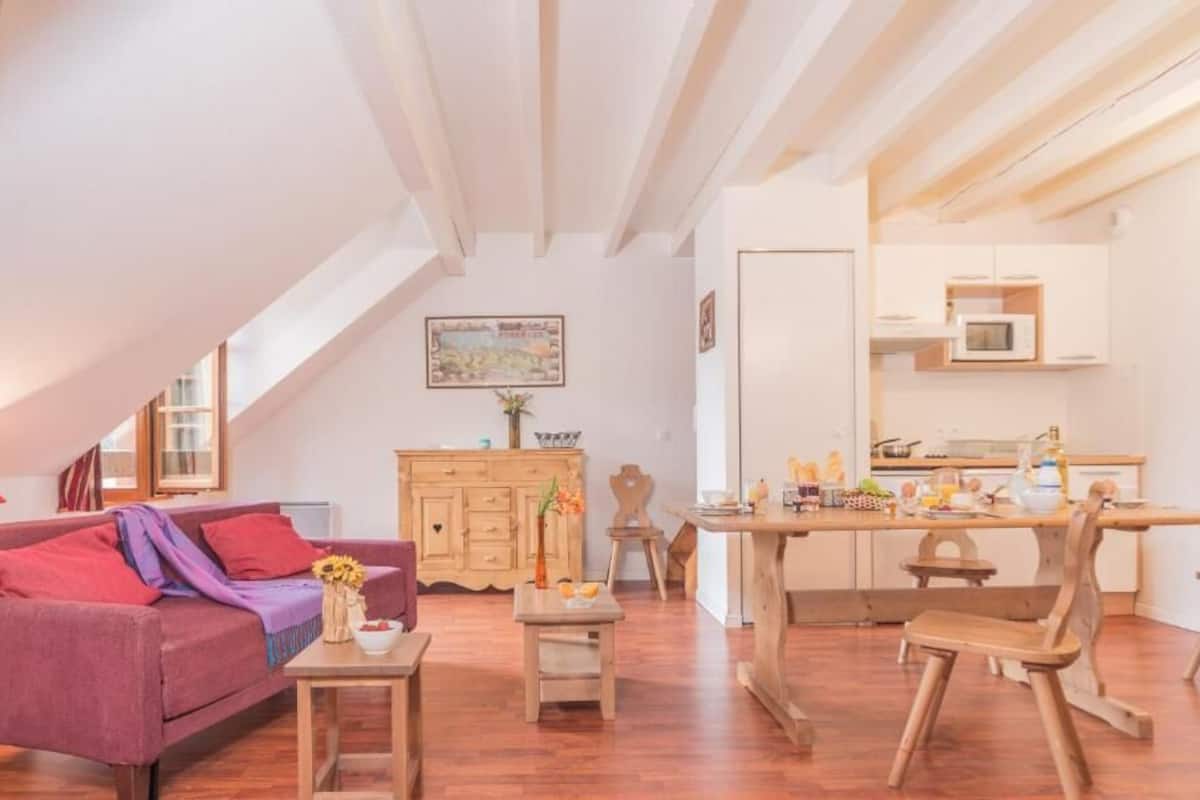 Un acogedor espacio tipo loft con comedor, mobiliario de madera y cocina equipada con electrodomésticos modernos.