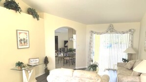 A living room with a sofa, a coffee table, and a dining area with chairs and a table. - Disney Area Budget Homes (Davenport)