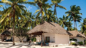 A beach resort with thatched-roof huts, palm trees, and a sandy beach. - Karafuu Hotel Beach Resort (Michamvi)