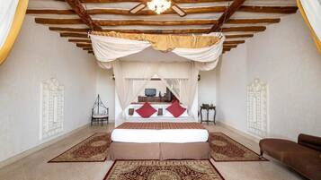 A bedroom with a canopy bed, a ceiling fan, and a large rug.
