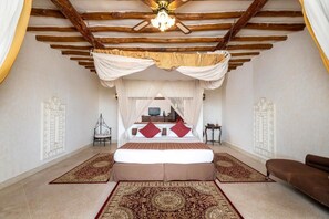 Un dormitorio con cama a dosel, ventilador de techo y alfombra grande.
