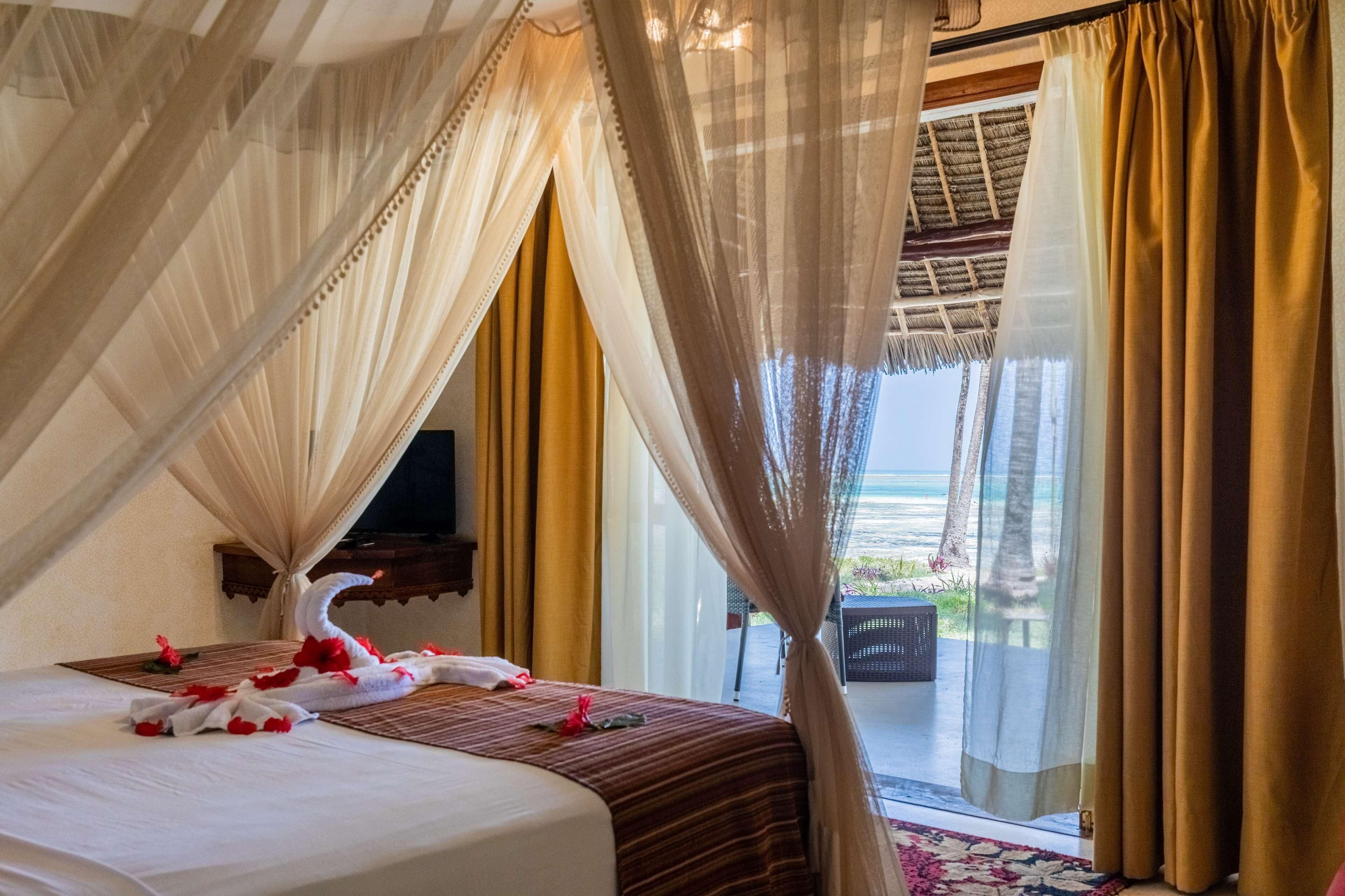 Een hotelkamer met een bed, een televisie en uitzicht op de oceaan.