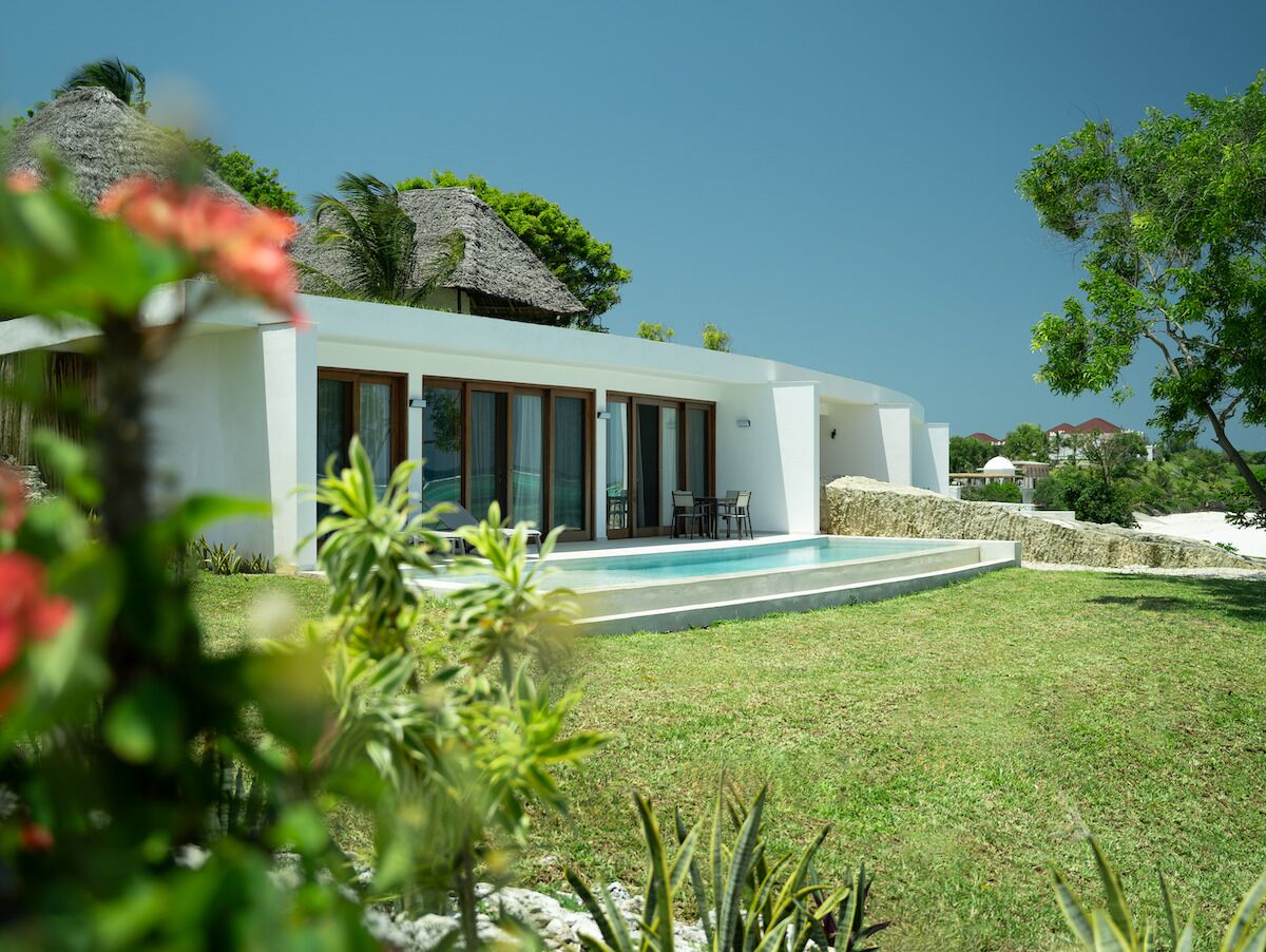 A modern house with a swimming pool, surrounded by a well-maintained lawn and tropical vegetation.
