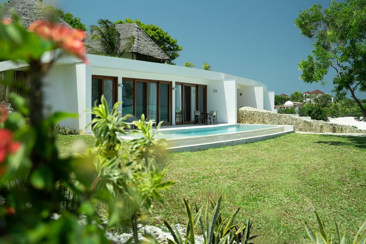 A modern house with a swimming pool, surrounded by a well-maintained lawn and tropical vegetation.