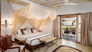 A bedroom with a bed, bedside tables, a chair, a bench, and a view of the outside. - Karafuu Hotel Beach Resort (Michamvi)