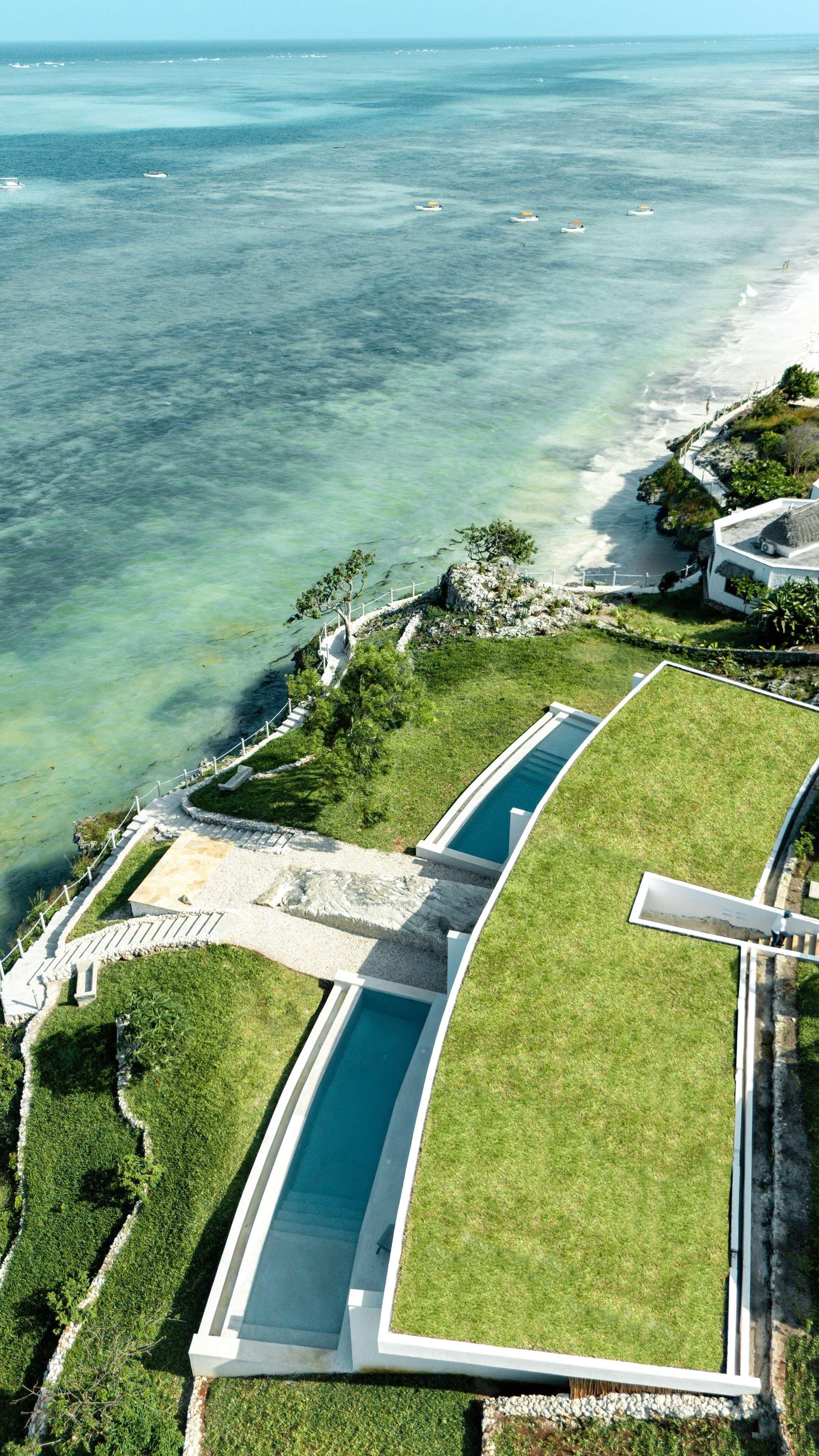 Vista aérea de um resort com piscina, águas cristalinas e uma praia.