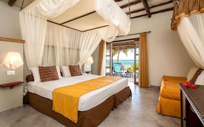 A bedroom with a bed, a bedside table, a chair, and a view of the ocean.