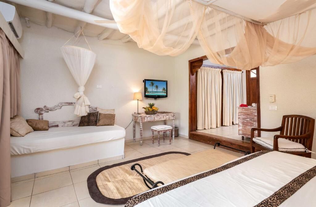 A bedroom with a bed, bedside table, chair, and a television on the wall.