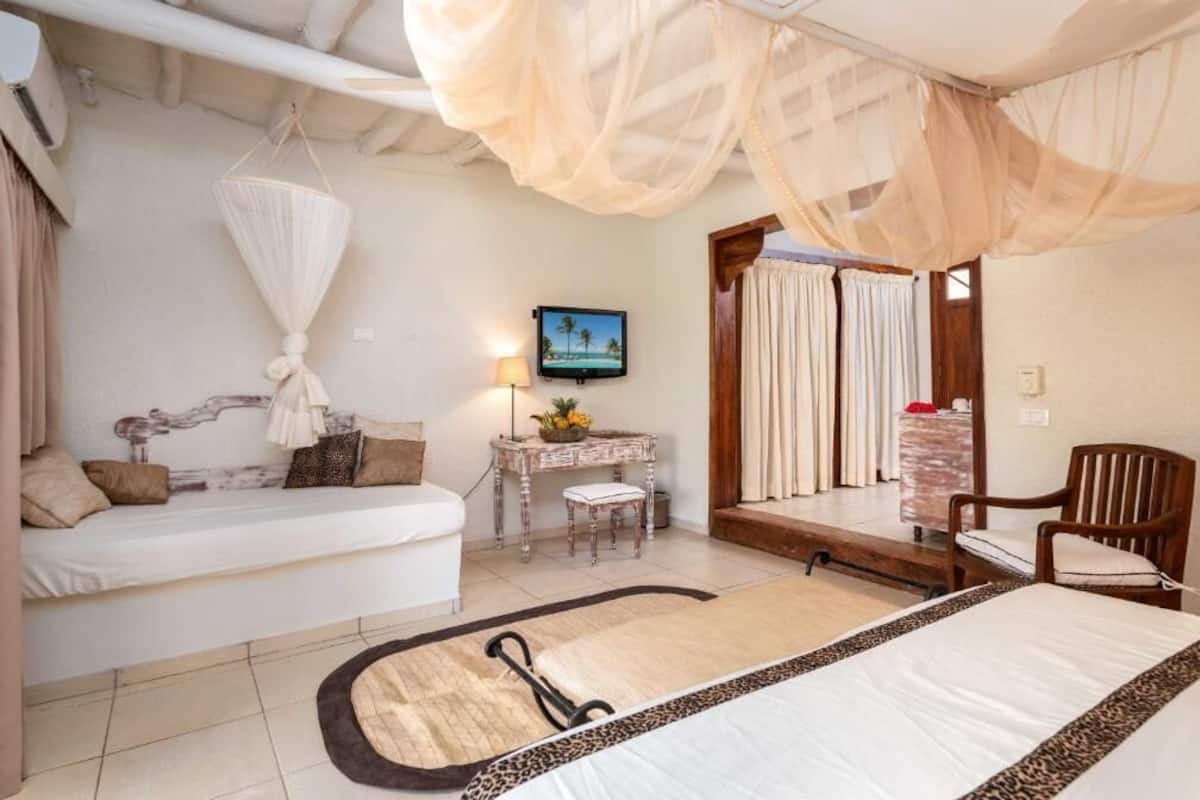 A bedroom with a bed, bedside table, chair, and a television on the wall.