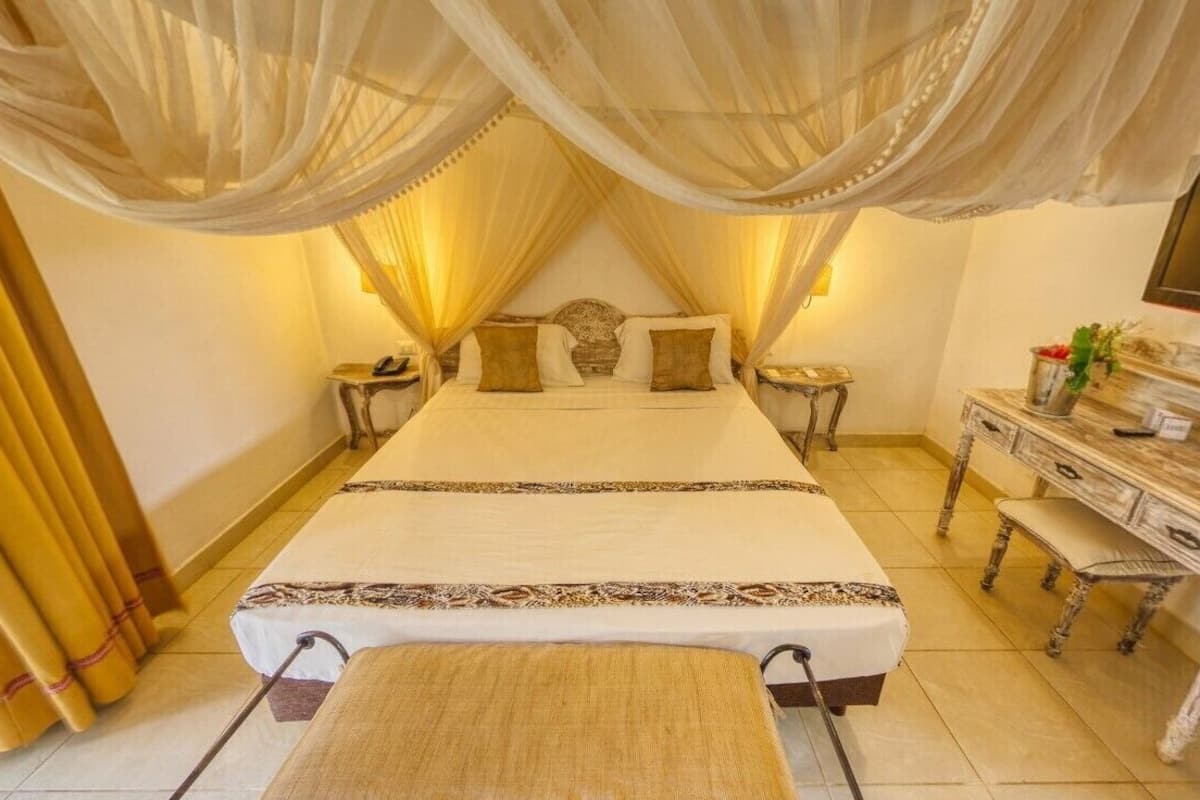 A bedroom with a large bed, a TV, a desk, and a chair.