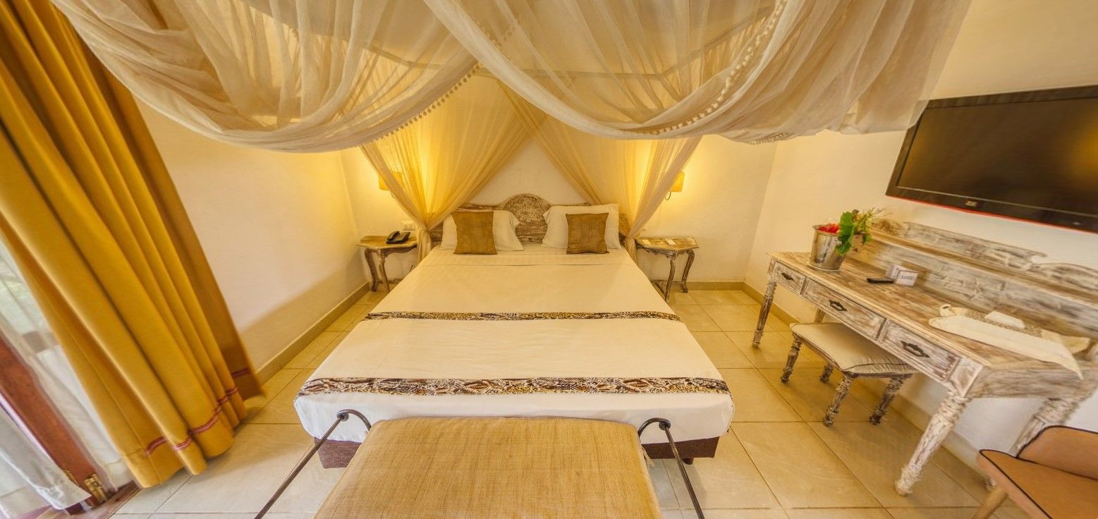 Quarto com uma cama grande, televisão, penteadeira com espelho e escrivaninha.