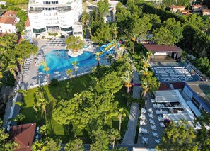 An aerial view of a resort with a swimming pool, a water slide, and a covered outdoor seating area. - Catamaran Resort Hotel (Kemer)